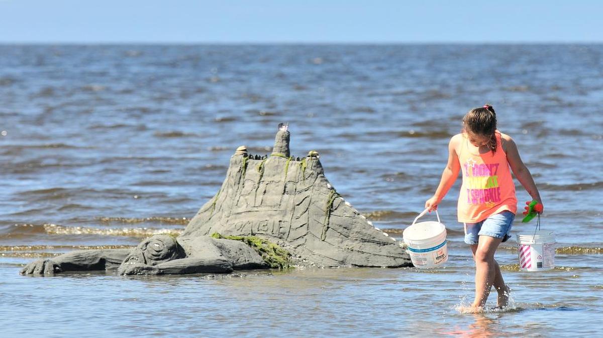 
Kalia Trent, then 8, of Blaine, walks past the sand sculpture “Zombies” as the incoming tide washes it away during the 2014 Birch Bay Sand Sculpture Contest. This year’s event is July 18-19.
