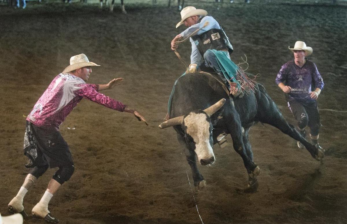 Bullfighters Matt Akers, left, and Ryan Manning move to help Lou Danley, center, dismount a bull during the 2018 bull riding competition at the Northwest Washington Fair.