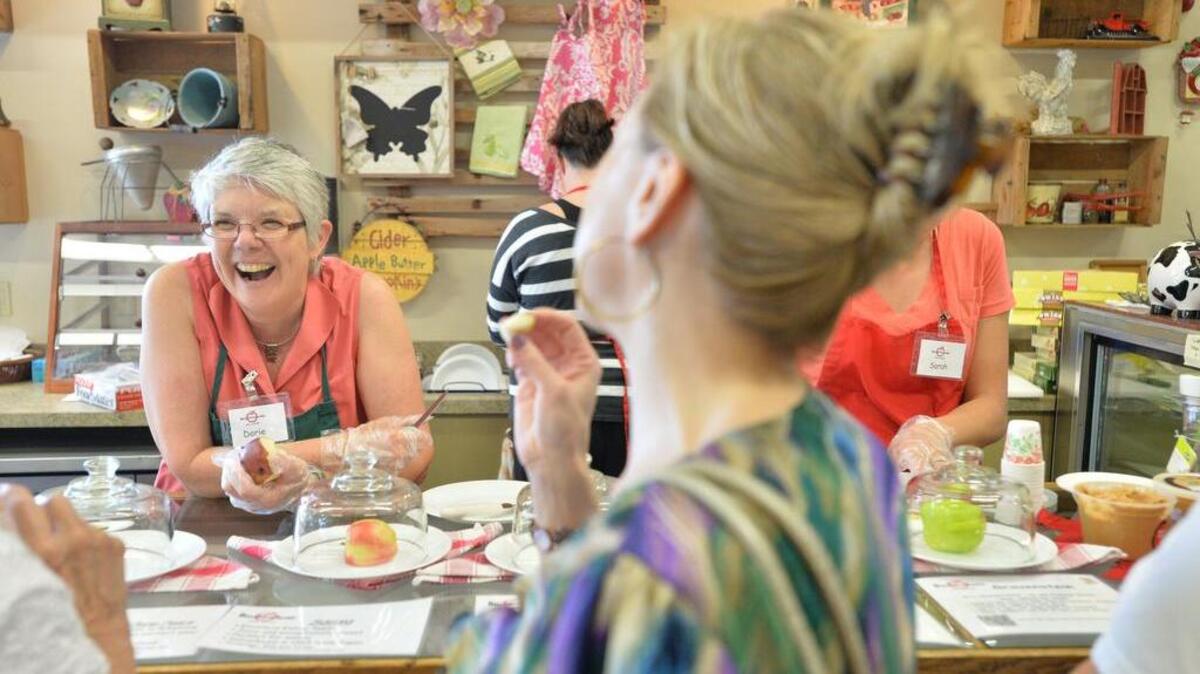 Owner Dorie Belisle, center, laughs with customers as they taste samples of apples at BelleWood Acres & Distilling on in 2013 in Laurel.