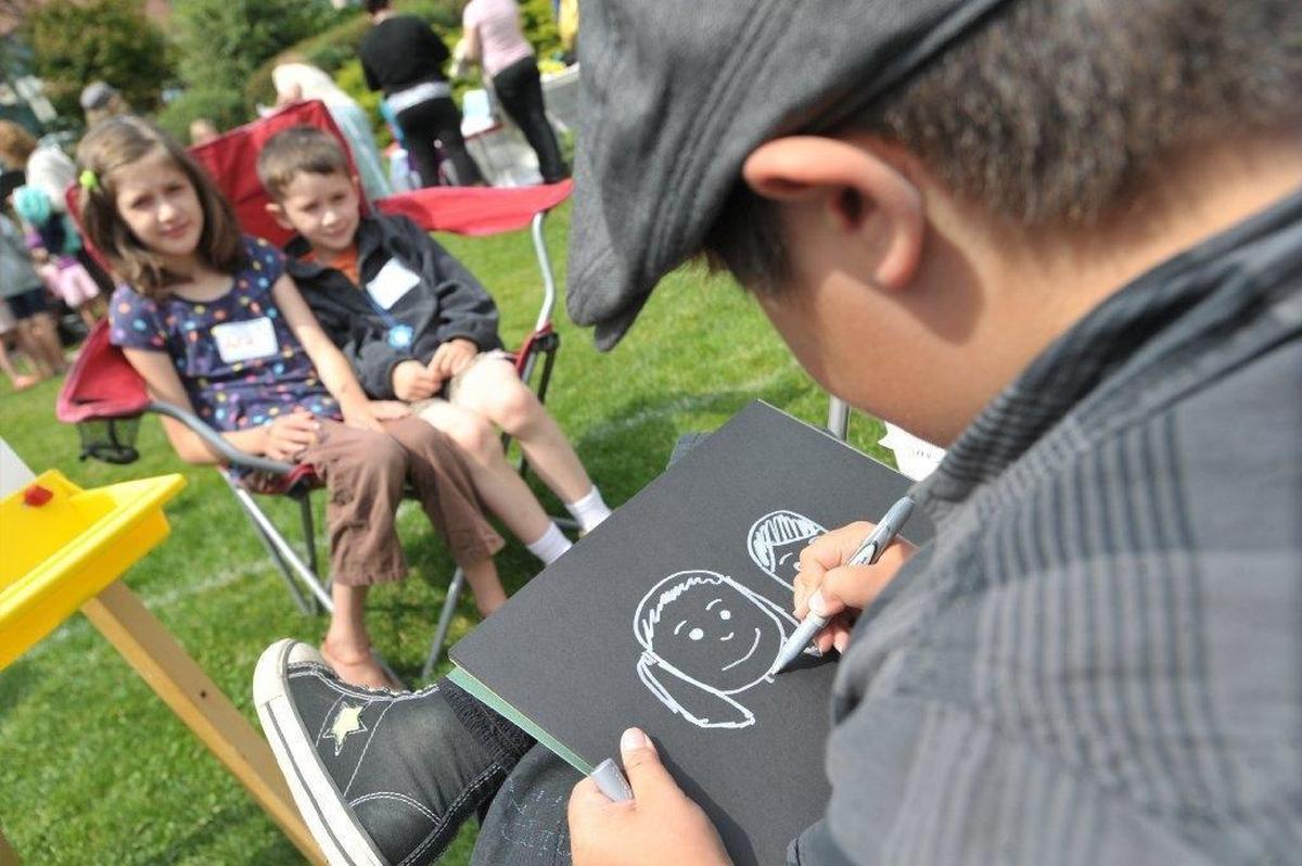 Max Oviedo, right, draws a caricature of Aviva, left, and Elisha Foster during the 44th Annual Children’s Craft Fair at the Bellingham Public Library in 2012.