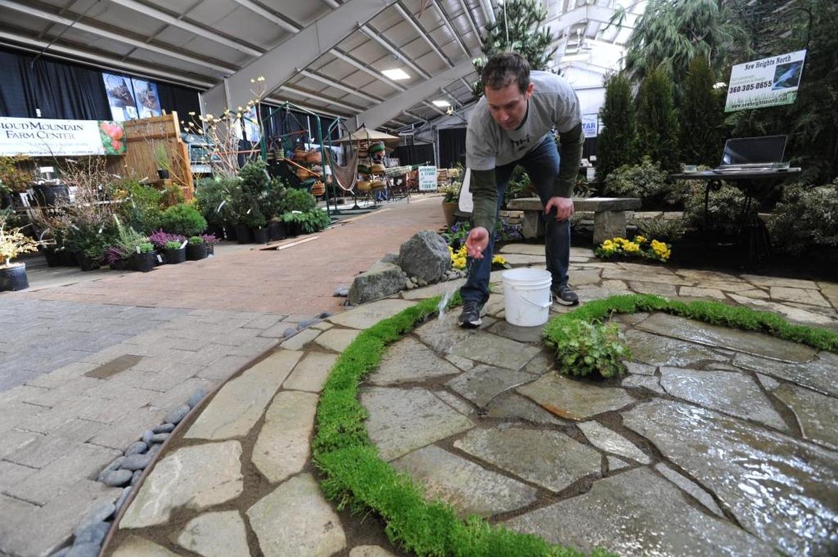 Ryan Sundholm of New Heights North splashes water on his exhibit at the 2013 Whatcom County Home and Garden Show at the Northwest Washington Fairgrounds.