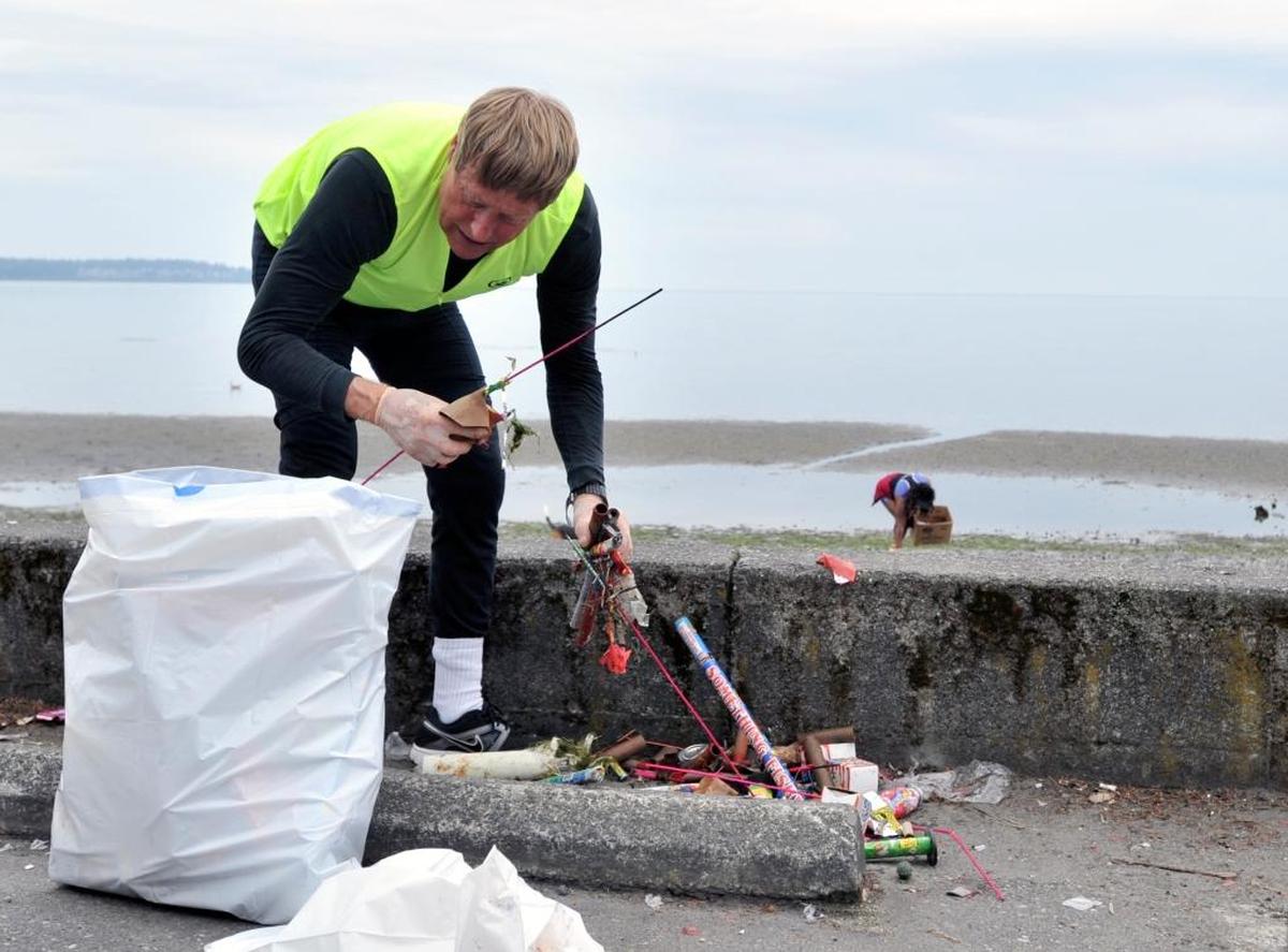 Pat O’Connor, left, and Sharon Censale, right, pick up fireworks and other debris left on the beach from Independence Day festivities on July 5, 2014, in Birch Bay.