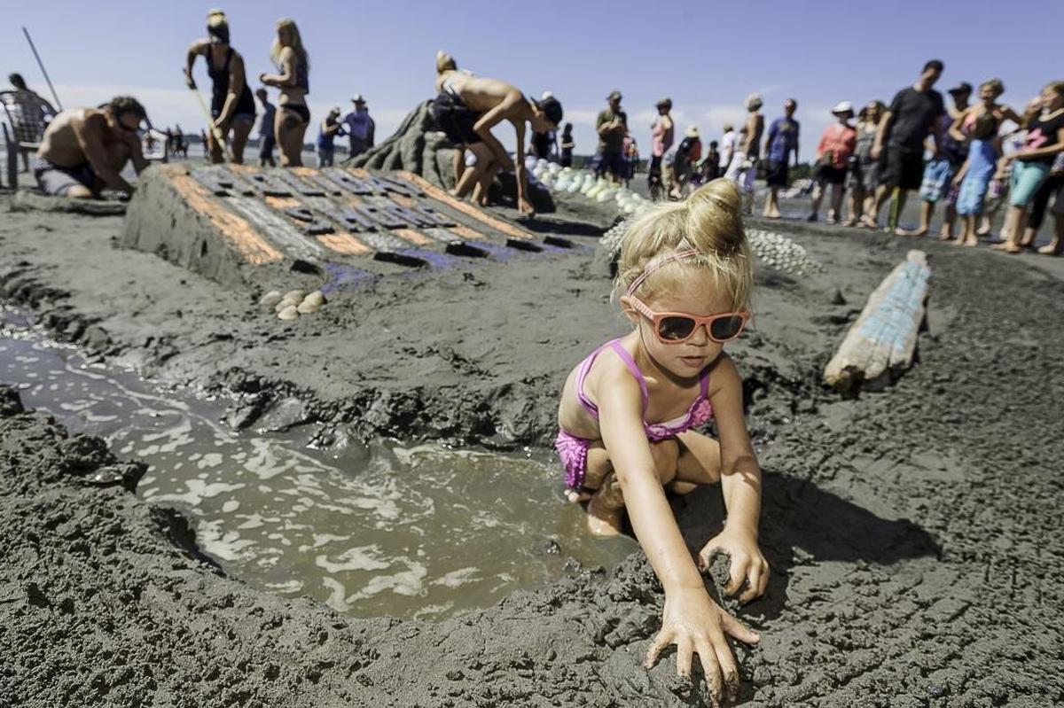 Macy Tjoelker of Lynden plays in the sand as family members work on a mermaid sand sculpture during the annual Birch Bay competition in 2015.