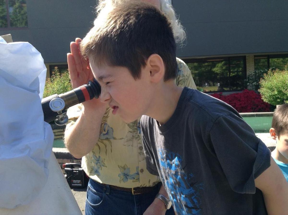 A child looks at the sun during a “sidewalk astronomy” event with the Whatcom Association of Celestial Observers in May at the Bellingham Public Library.