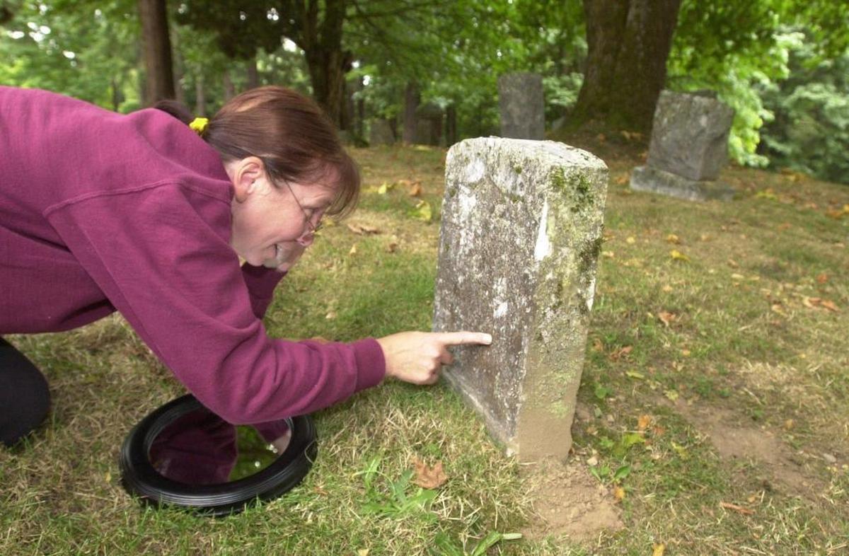 A visitor to Bayview Cemetery examines the weathered gravestone of Civil War veteran Emmet Ryns, 7th Kanas Calvary.
