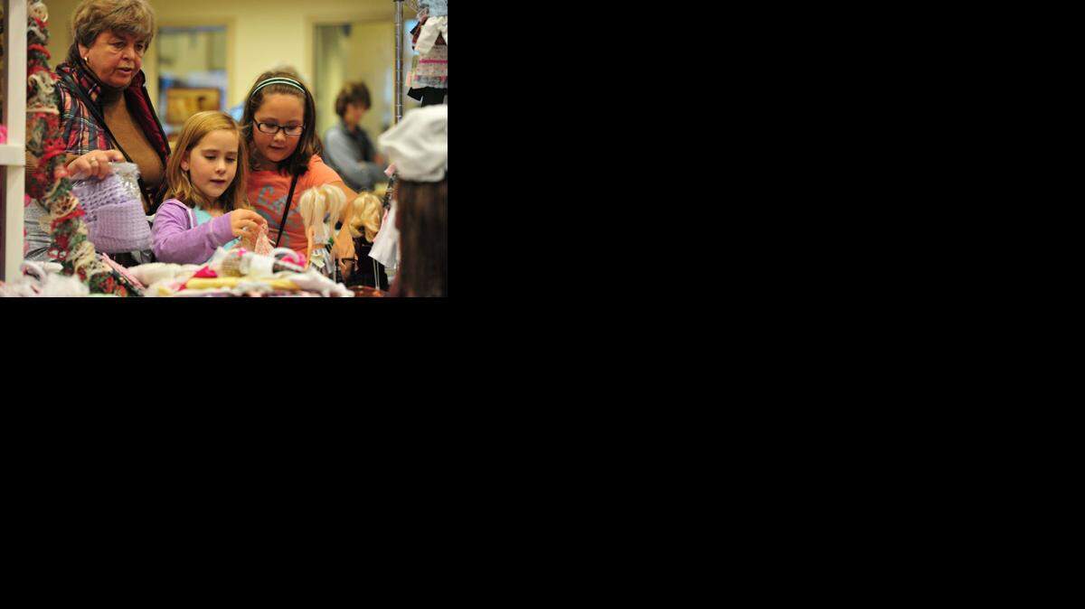 Pam Moore (left), granddaughter Ellie Pursley, 8, and Macie McMillen, 8, pick out handmade doll clothing at the Hillcrest Chapel Holiday Arts and Crafts Fair on Nov. 2, 2013, in Bellingham.