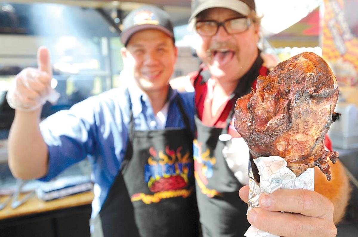 Arnold Lim, left, and Craig Sawyers, owner of Piggly's BBQ and Grill, hold out a 1.5 lb. turkey leg at their food stand, one of the delicious offerings at the Northwest Washington Fair.