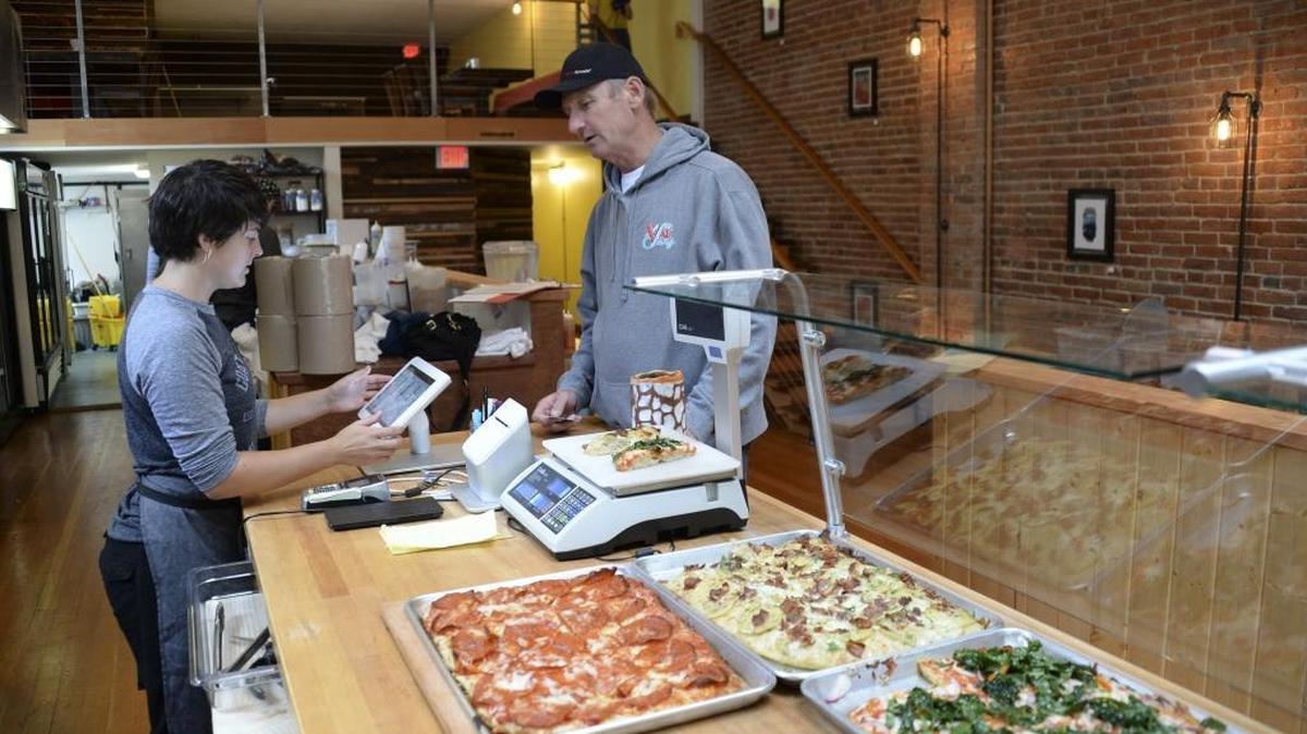 Employee Holly Strauch takes an order from customer Ryan Stiles at the new location of Goat Mountain Pizza on July 7 in downtown Bellingham. The pizza restaurant recently opened in the former Film is Truth space on West Holly Street.