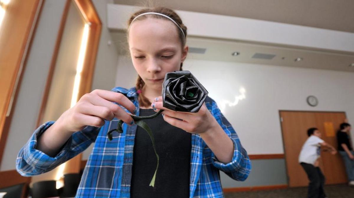 Anny Olson wraps the stem of her black ribbon rose during an Anti-Valentine's Day event at Lynden Library in 2012.