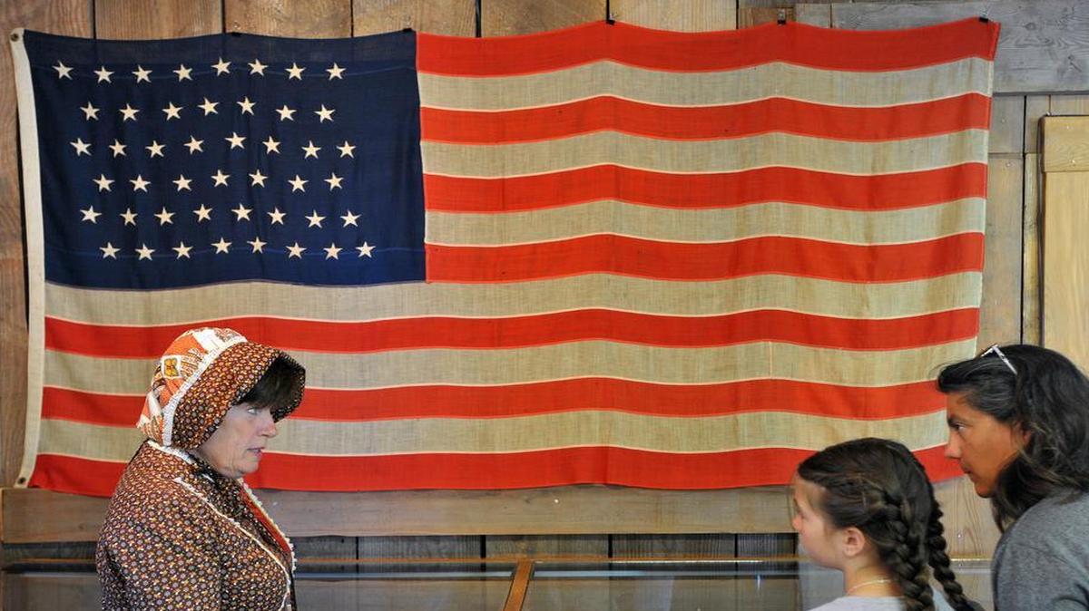 
Nancy Knapp, left, explains the history of the 46-star flag to Vanessa and Alisha Whitaker, right, inside the Veterans Museum during the 2013 Old Settlers Picnic in Ferndale’s Pioneer Park.
