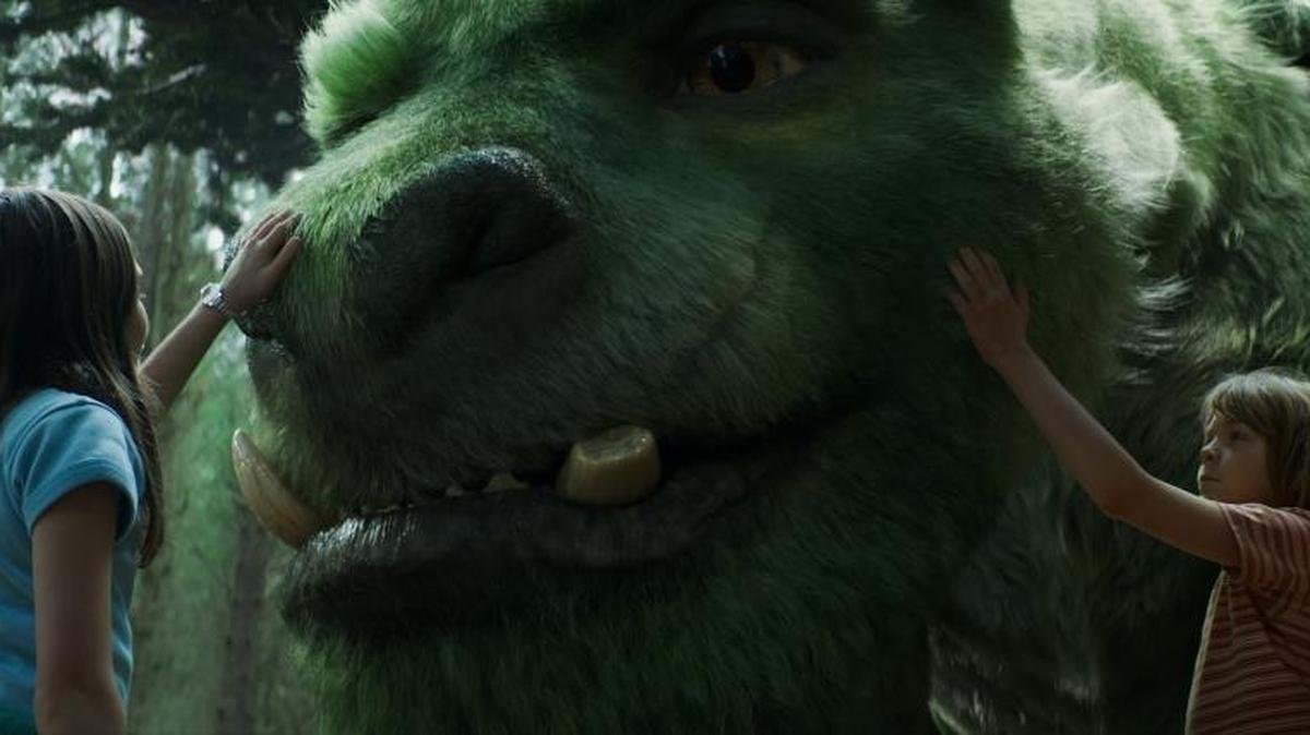 Oona Laurence, left, plays Natalie and Oakes Fegley, right, appears as Pete, right, with Elliot the dragon in “Pete’s Dragon.”