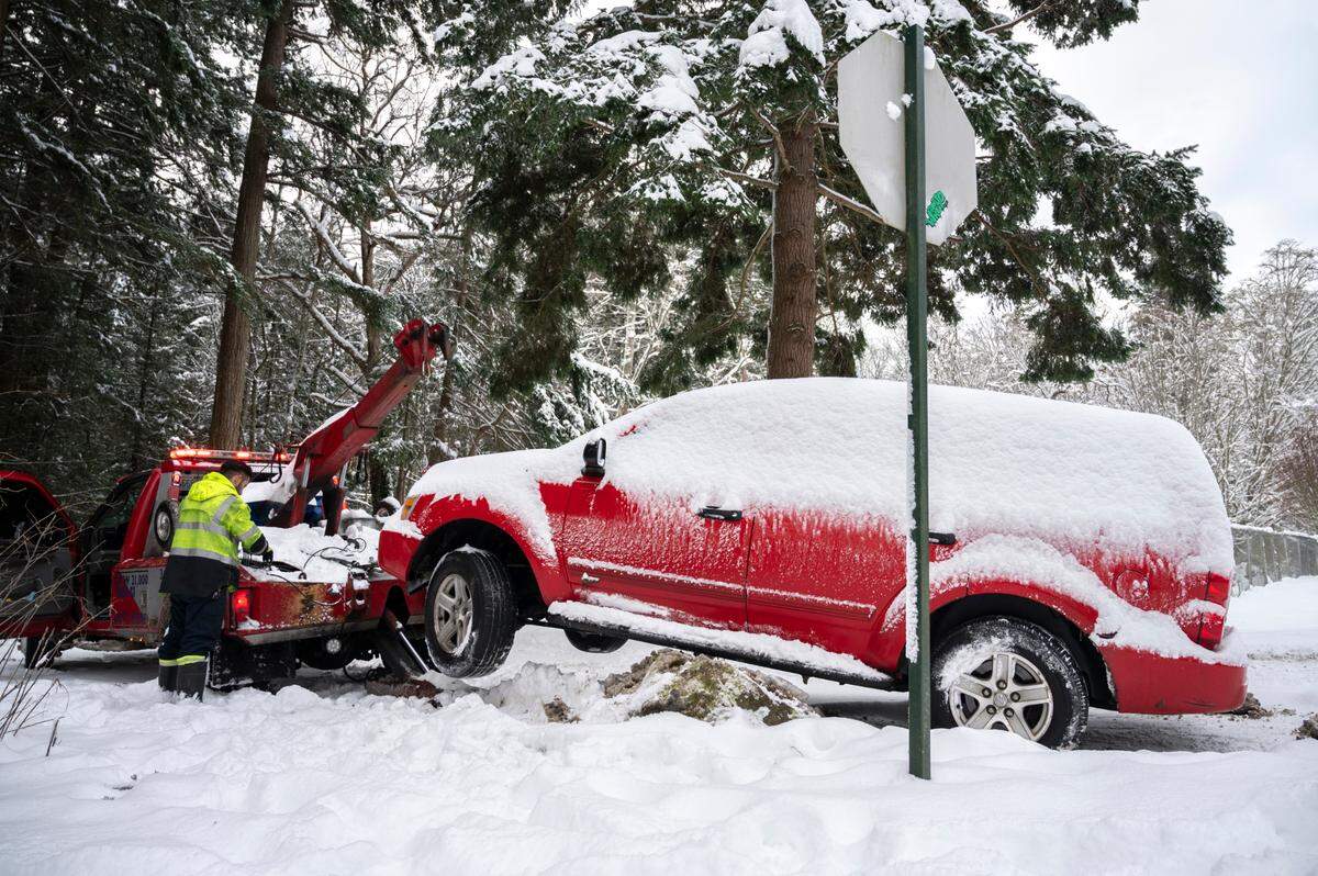A vehicle that slid of the road and got stuck on a rock is recovered by a tow company near Lake Padden on Dec. 30, 2021, in Bellingham.