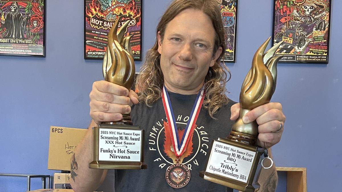 Funky’s Hot Sauce owner Matthew Mini display multiple awards the company earned at the 2025 New York City Hot Sauce Expo.