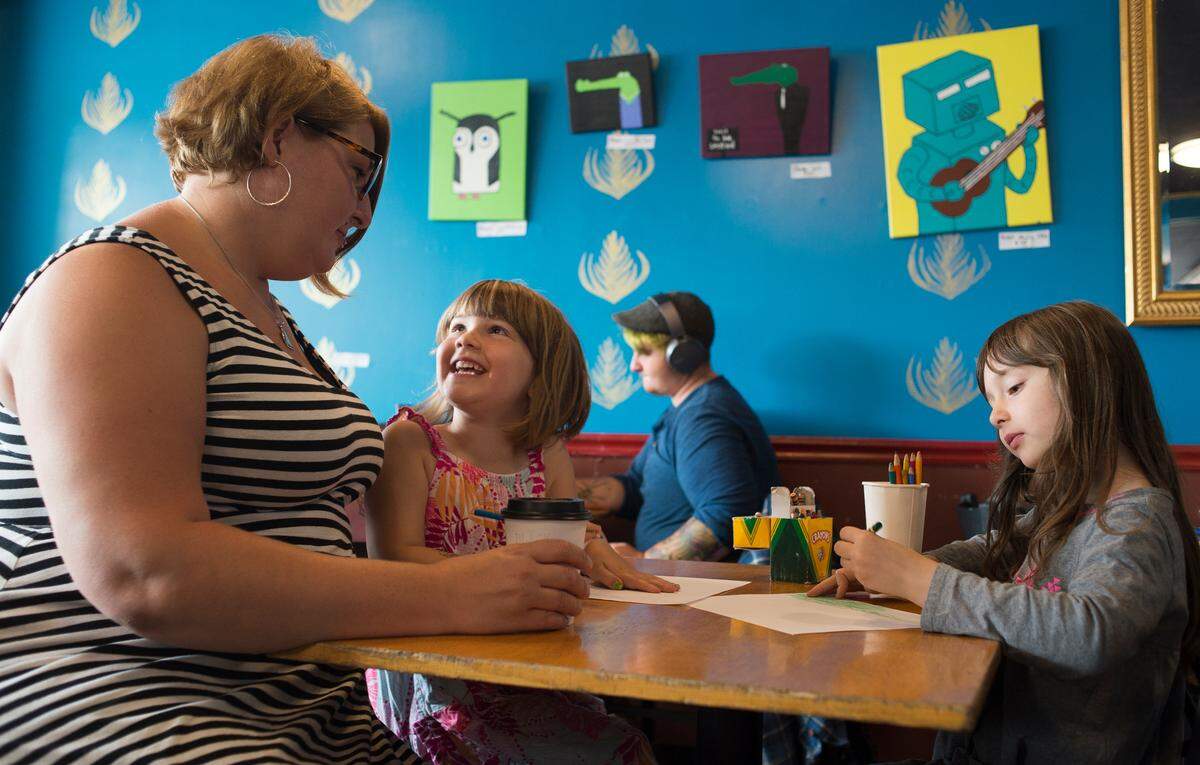 Stephanie Oppelaar, co-owner of the Black Drop Coffeehouse, sits with her daughters Beatrice and Edith while they draw pictures at the Bellingham business.
