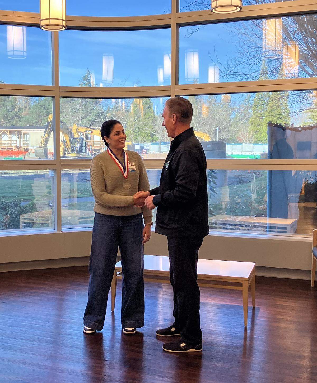 Dr. Ralph Weiche, Whatcom EMS Medical Program Director, awards Manpreet Sandhu with a medal for saving the life of a woman who went into cardiac arrest while watching the Bellingham Bay Marathon. Sandhu is a PeacHealth nurse who provided CPR to the woman before administering a AED shock.