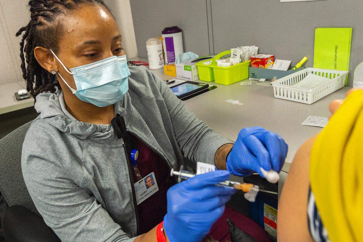 Licensed practical nurse Ivory Royal administers the second shot of the Pfizer COVID-19 vaccine to Piyada Kuankitpaisam of Bellingham on Feb. 20 at PeaceHealth St. Joseph Medical Center in Bellingham. The vaccine clinic was held for hospital employees.
