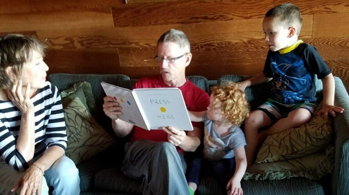 Don Alderson, second from left, reads to his grandchildren Charlie, right, and Ellyse, while longtime girfriend Mayrus Helberg listens in 2016 at a cabin in Blaine.