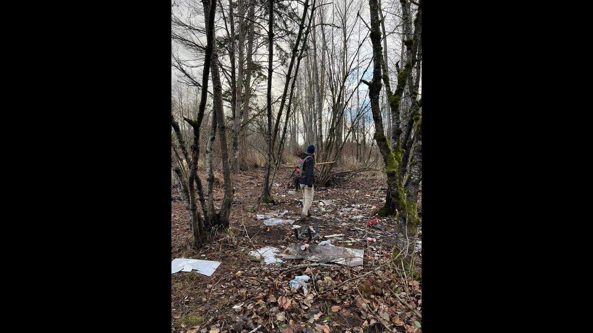 A volunteer cleans up trash the site of a new 18-hole disc golf course along West Bakerview Road in Bellingham.