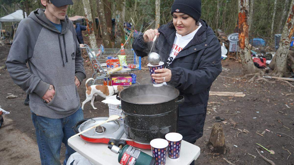 Hanah Warthan serves hot cocoa to unhoused residents of the encampment behind Walmart on Dec. 29, 2023, in Bellingham, Wash.