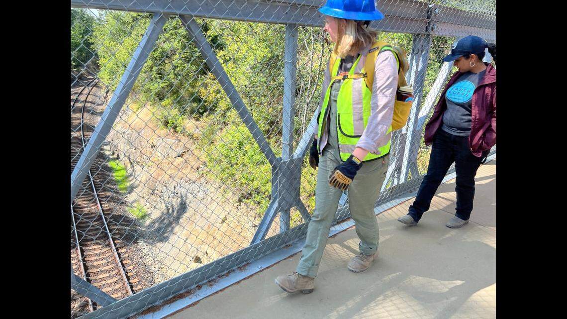 Earth Corps members from left, Anna Jowell, project manager, and Evlyn Andrade, executive director, cross the new railroad bridge over the BNSF tracks on the way to Clayton Beach at Larrabee State Park south of Bellingham, Wash.
