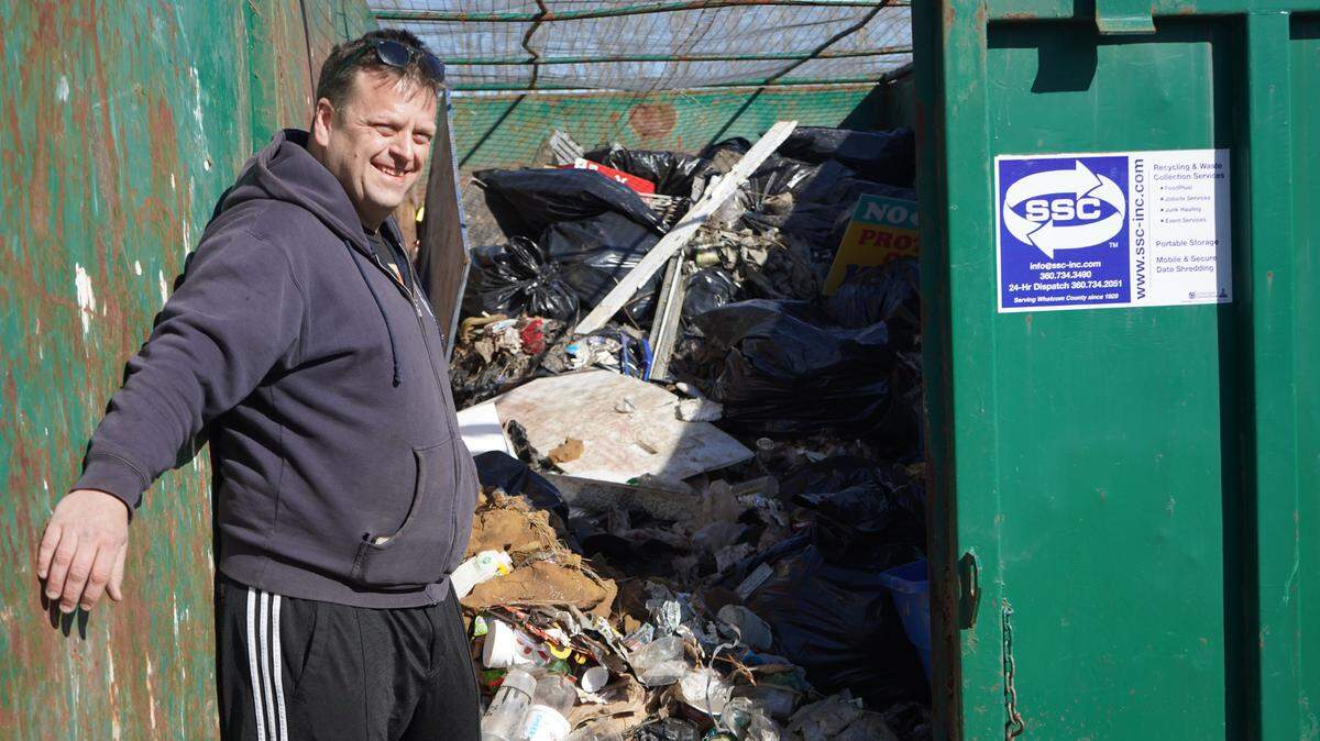 Whatcom Disc Golf Club board member Mikkel Hong stands in front of a dumpster on Tuesday, March 28, on a plot of land along West Bakerview Road in Bellingham. The trash was cleared to make way for a new 18-hole disc golf course.