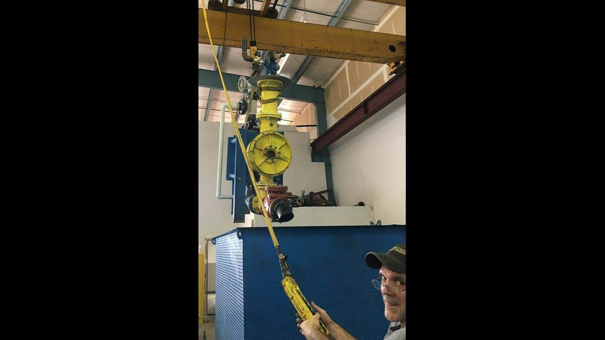 David Dibley lowers the Slurry Pulsejet Engine into a tank for submerged testing in a slurry tank.