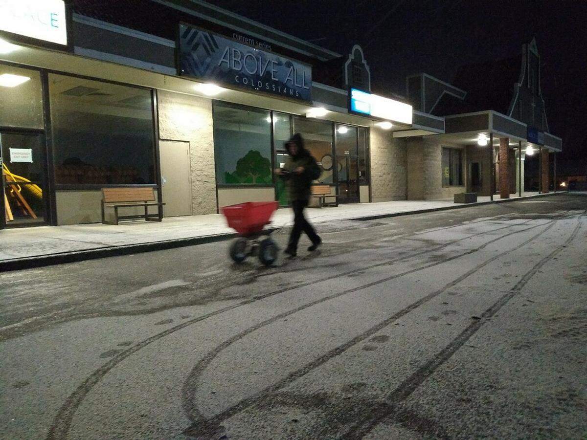 Shaun Holtorf of Lynden spreads de-icer in a parking lot at North County Christ the King Church in Lynden Friday morning.