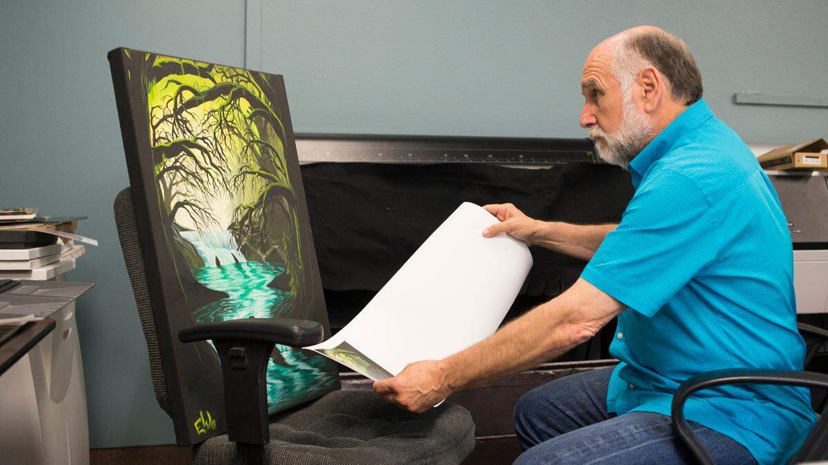 Employee Alan Sanders compares a small test version of a canvas print reproduction to the original artwork at Quicksilver Photo Lab in Bellingham.
