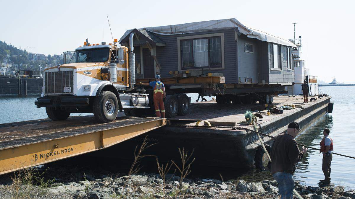 Boyer Towing and Nickel Bros employees work to take a house off of a tugboat on Wednesday, Sept. 5, at Landings at Colony Wharf in Bellingham. 