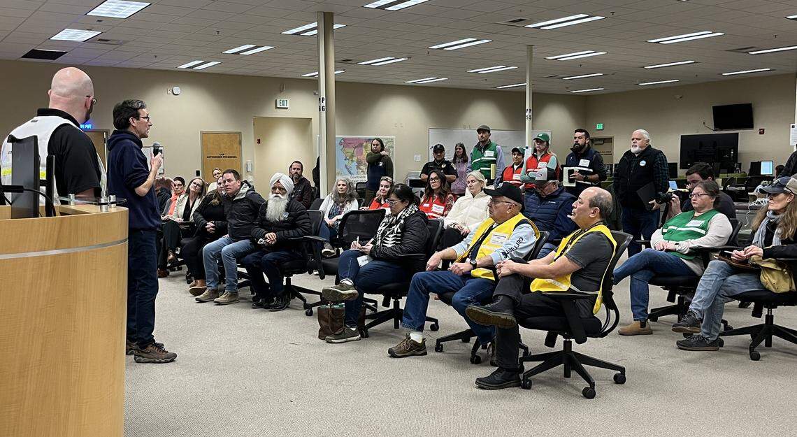 Washington Gov. Bob Ferguson, left, addresses Whatcom County Emergency Operations Center personnel and local government leaders in Bellingham on Wednesday, Dec. 17, 2025.