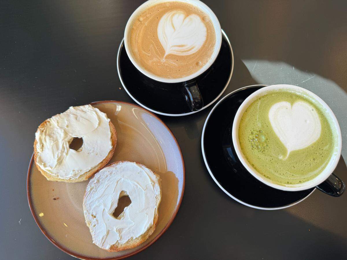 A garlic bagel with cream cheese, a vanilla latte and matcha latte from Daytrip Cafe.