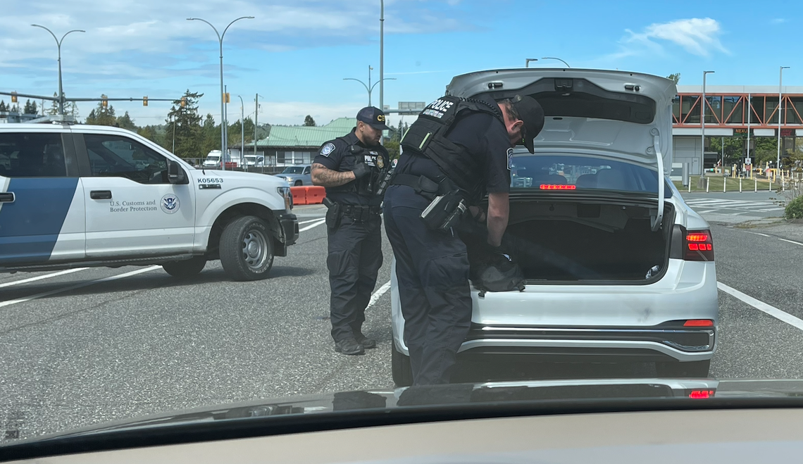 Customs and Border Protection officers search the trunk of a car by the U.S.-Canada border.