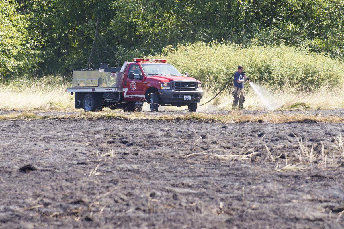 A firefighter from North Whatcom Fire and Rescue puts out remaining hot spots in a field on Friday, on Bay Road near Birch Bay.