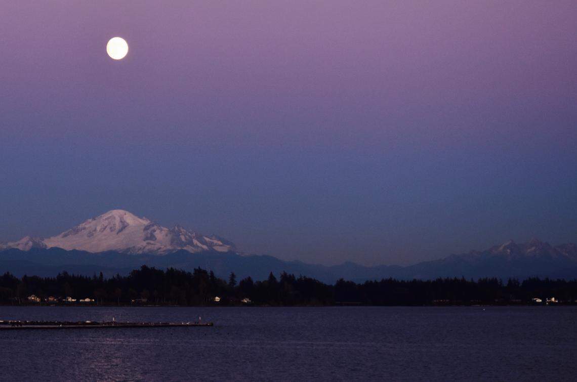 The moon rises over Drayton Harbor at Semihamoo Spit, throwing its glow on Mount Baker and the Twin Sisters.