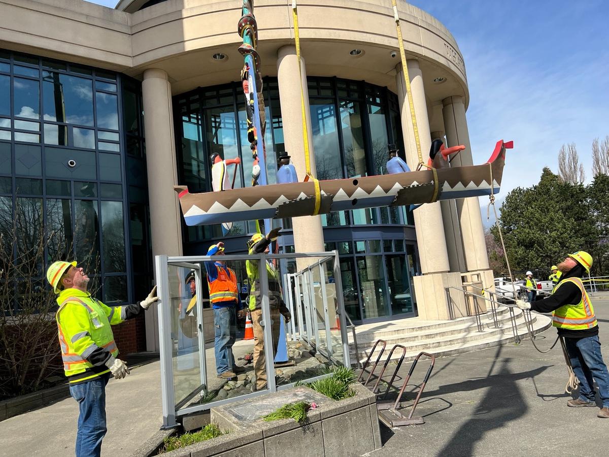 Whatcom County workers guide the canoe base of a Lummi Nation story pole into place at the County Courthouse in downtown Bellingham on Thursday, April 13. The story pole, which depicts the tribal chief, his brother and two early European settlers, was created in 1952 to mark the event’s centennial. It was removed for restoration after it was vandalized in early 2021.