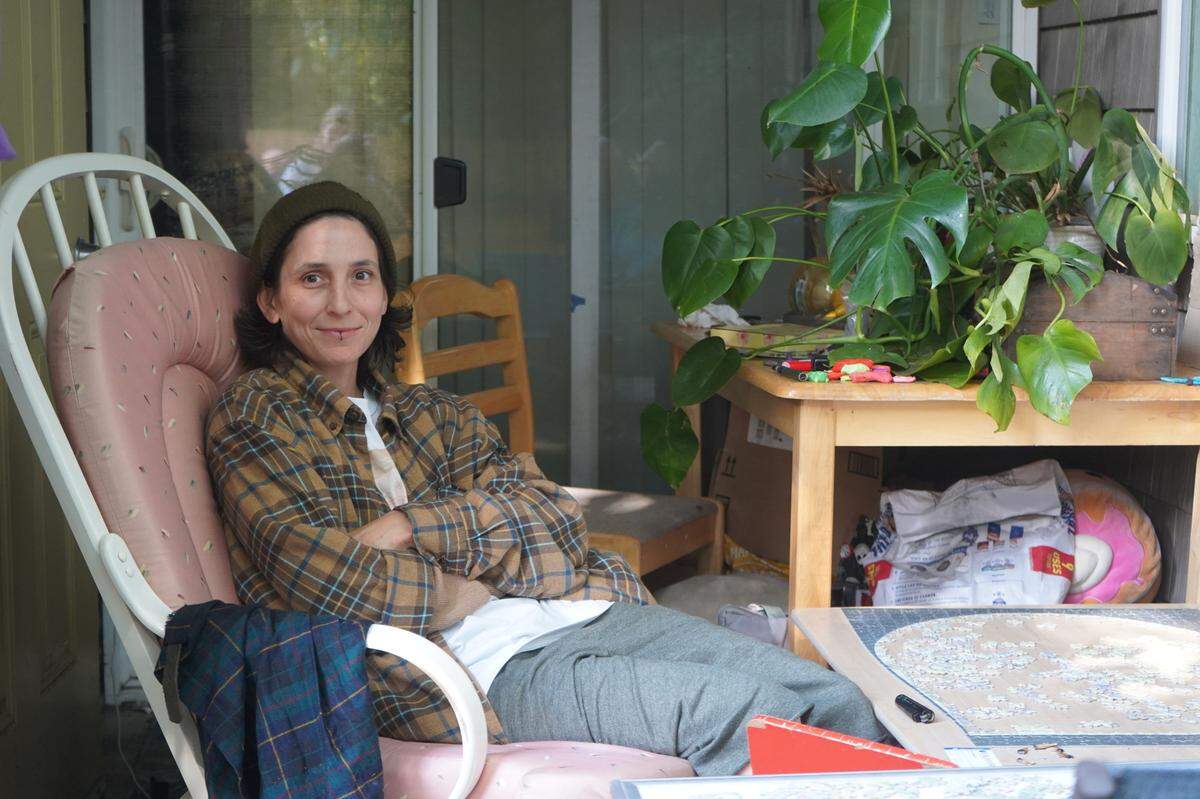 Sara Wellman sits on the patio at her Meadow Wood Townhomes residence on Sept. 22, 2023, in Bellingham, Wash. Wellman has lived at Meadow Wood for about four years and had her unit fully flooded in June of 2023 due to a broken water heater.