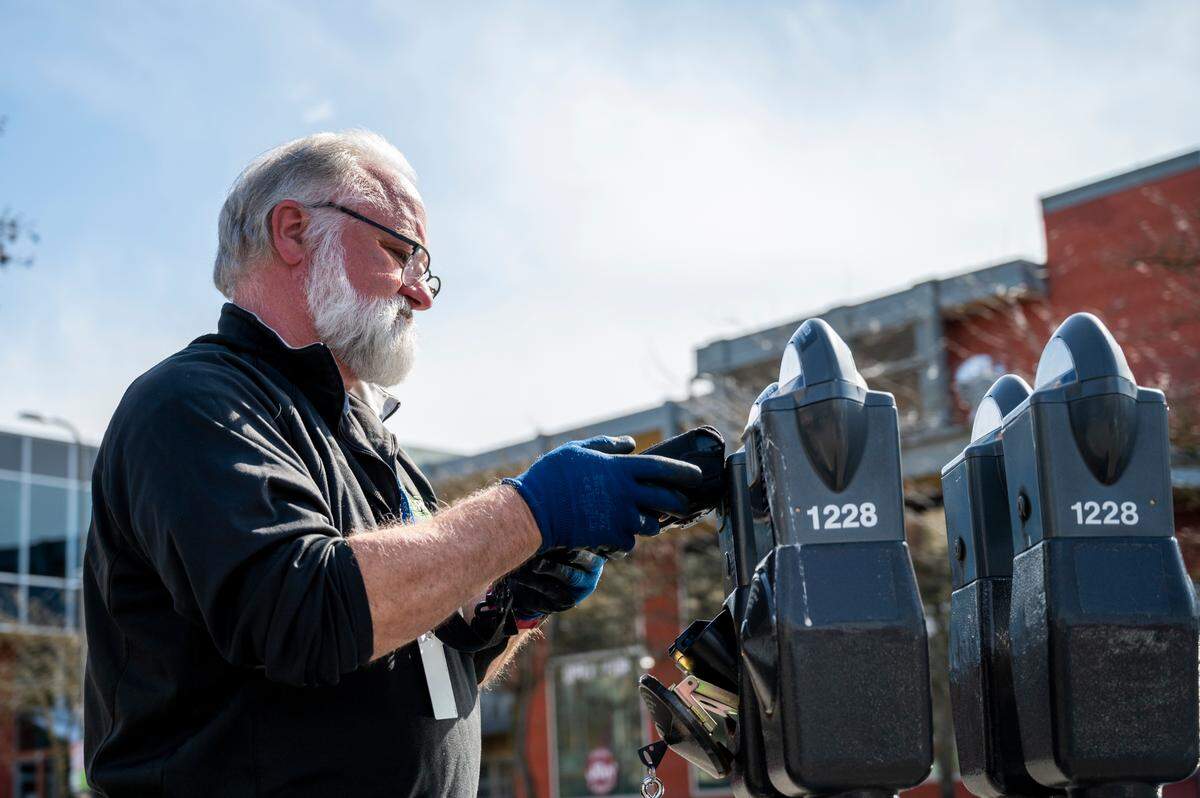 Ross Gerard removes coins from parking meters on Thursday, April 14, in downtown Bellingham.