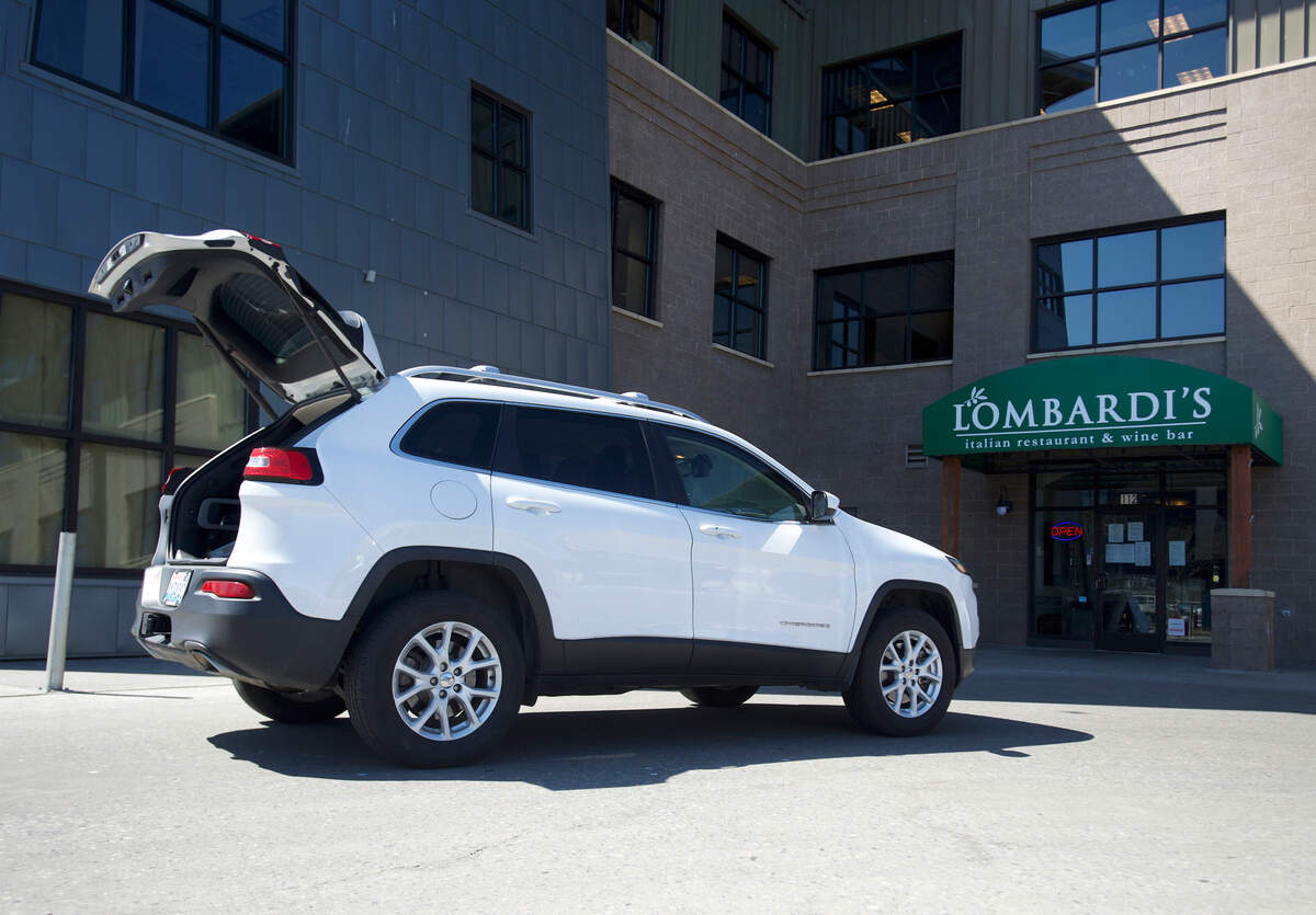 A customer waits to have a grocery order from Lombardi’s restaurant loaded into their vehicle on Thursday in Bellingham. Lombardi’s is offering curbside pickup because of the coronavirus pandemic.