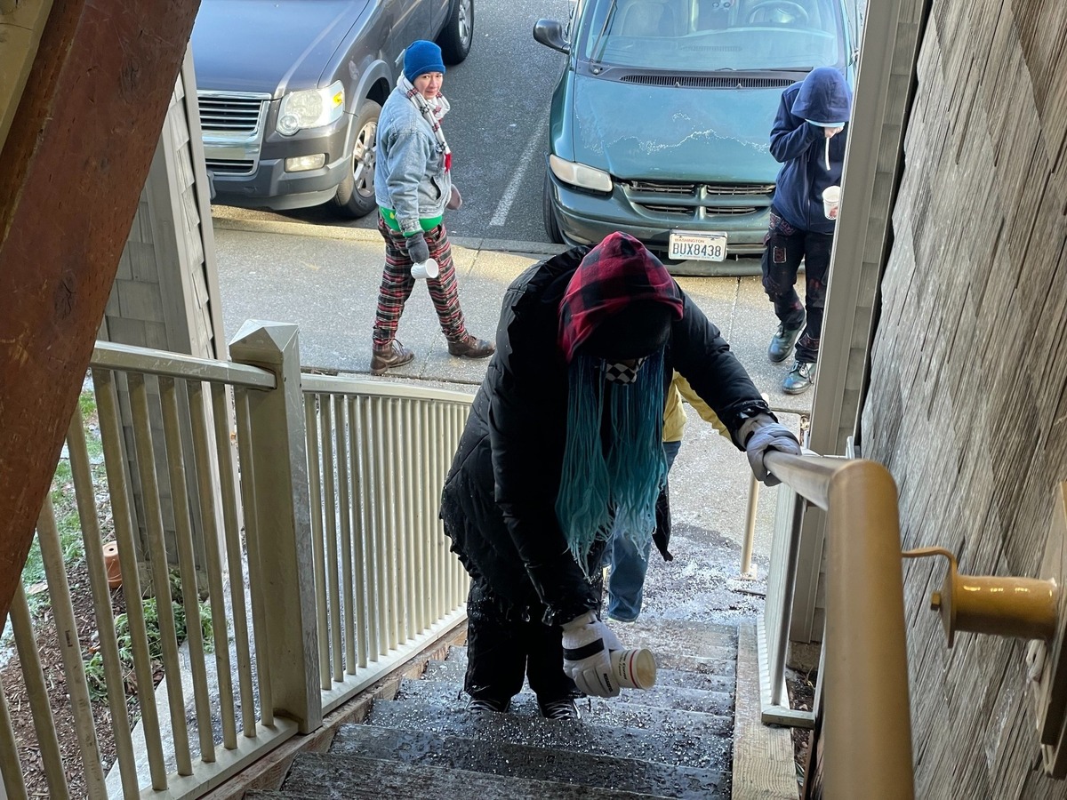 Meadow Wood Townhomes residents spread salt on the stairway to prevent ice from forming after fire sprinklers burst and flooded units during January’s record freeze event in Bellingham, Wash.