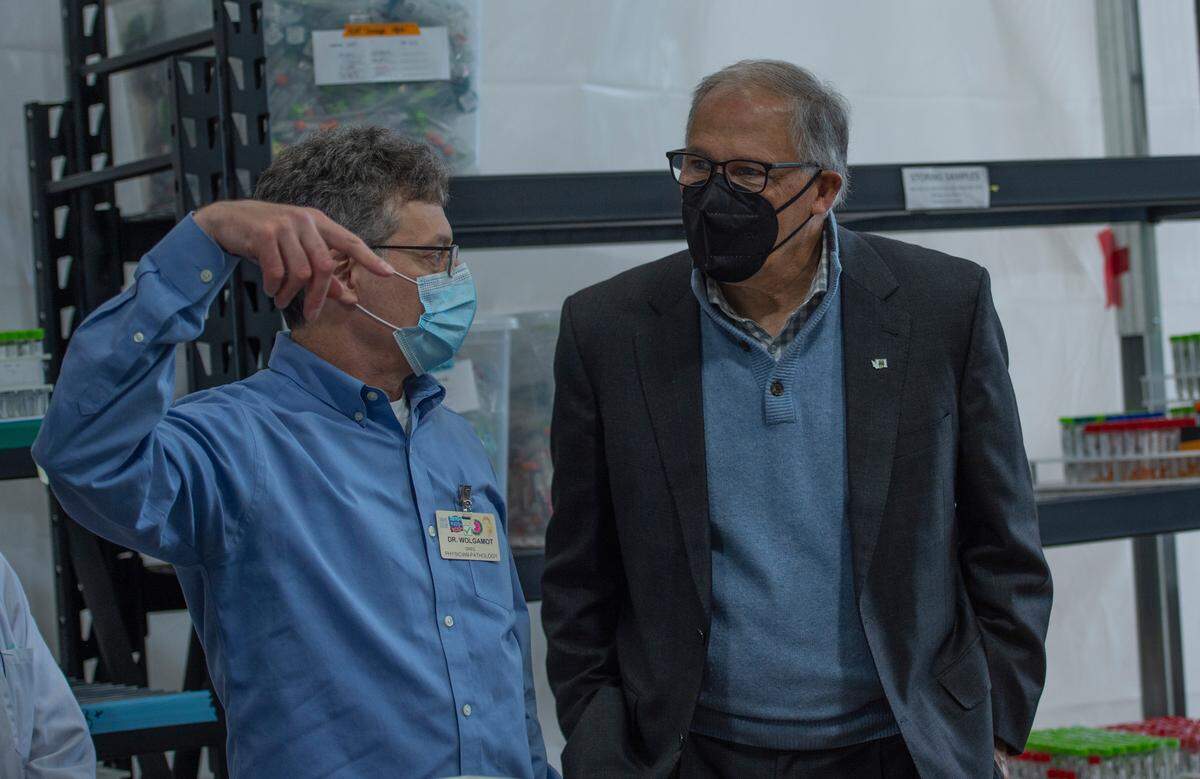 Washington state Gov. Jay Inslee listens to Dr. Greg Wolgamot, a pathologist at Northwest Laboratory, during a visit to the facility that does COVID-19 testing on Tuesday, Oct. 12, in Bellingham.