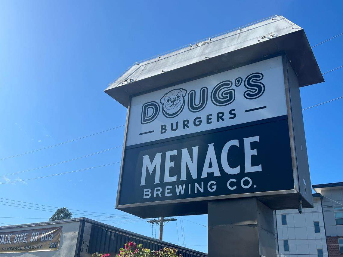 A sign for Doug’s Burgers stands outside the restaurant’s brick-and-mortar business, located next to Menace Brewing Co.