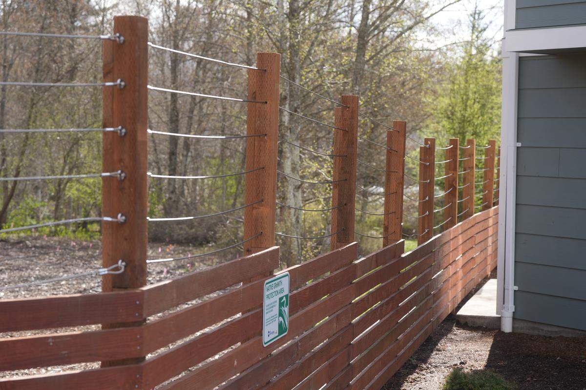 Tall fencing lined the property of a newly-built rental townhome community on Tull Road on March 26, 2026, in Bellingham, Wash. The developers say they had to install the fencing to keep activity from the nearby encampment from encroaching on the housing.
