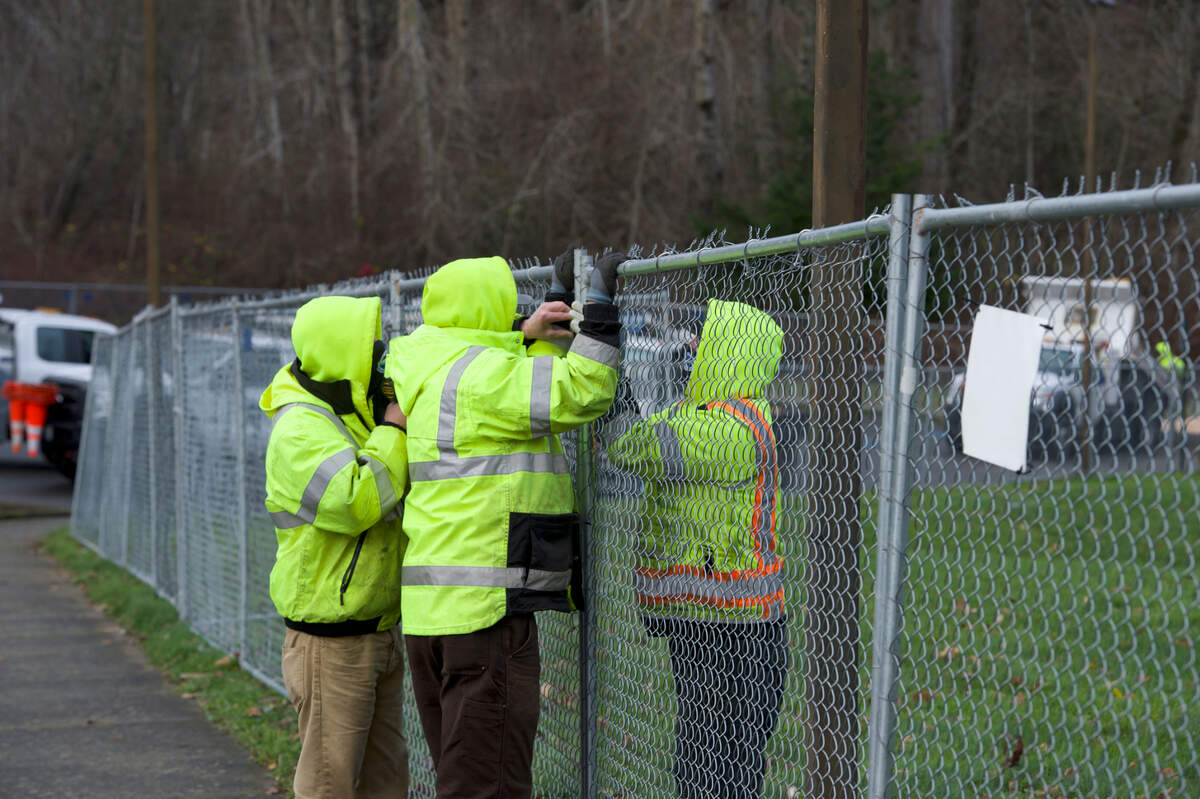 Employees from the city of Bellingham erect fencing around the location for a temporary encampment for people who are without housing on Friday, Dec. 11, at Geri Fileds in Bellingham.