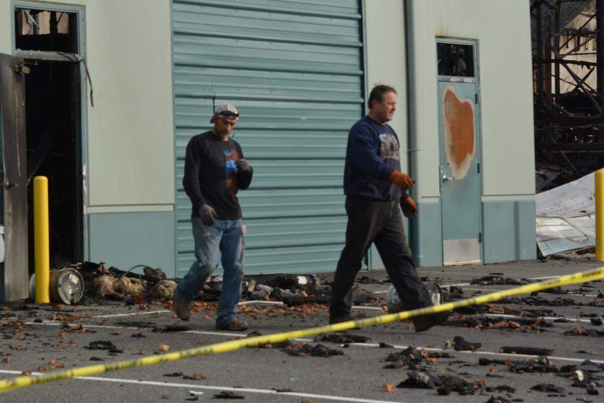 Shawn Robert, left, and Stepan Baydak of Scrap-It install fencing around the damaged Blue Sea Systems building Monday in the Cordata area.