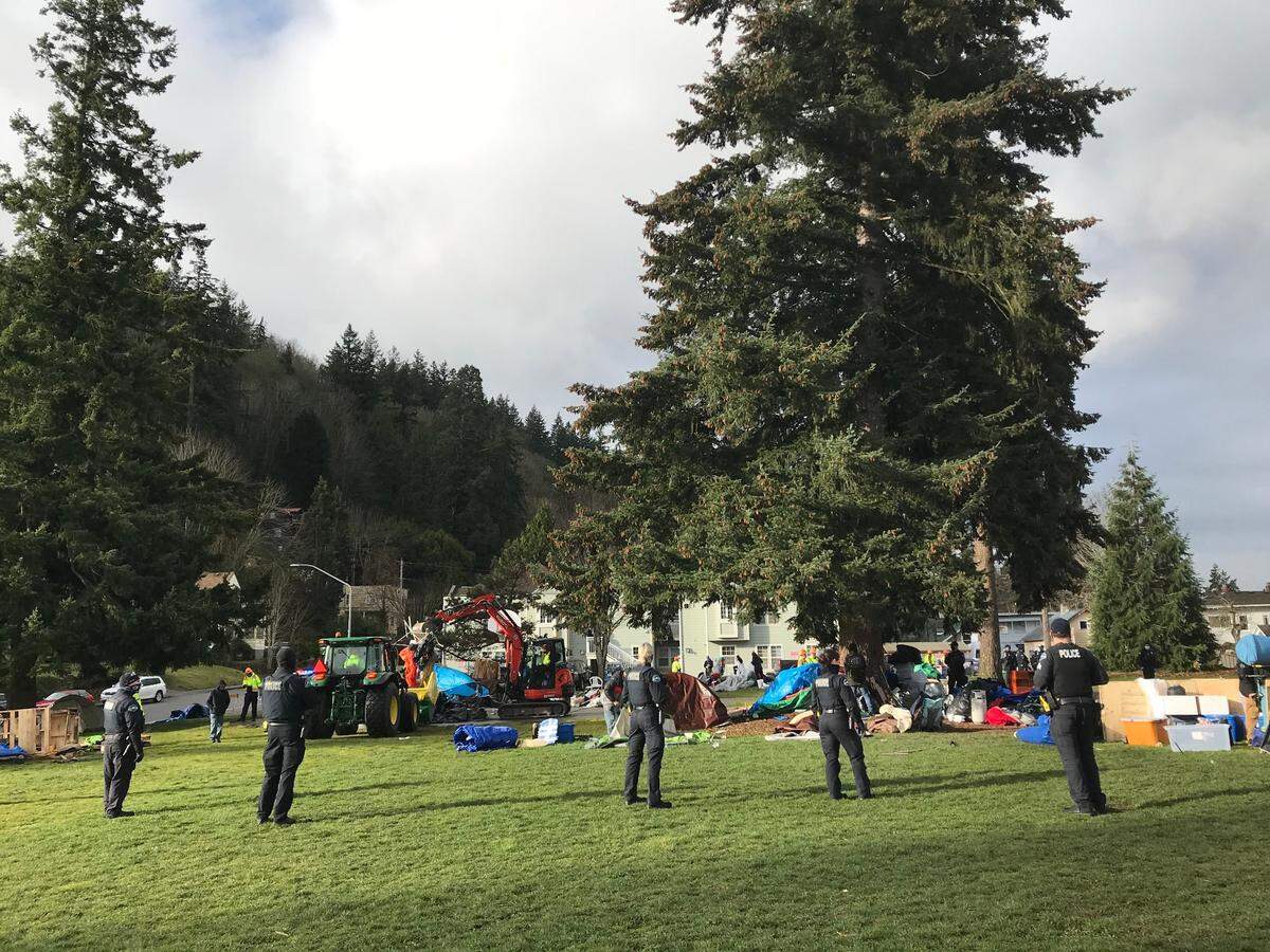 Bellingham Police officers stand by as city work crews dismantle a homeless camp at Laurel Park in Bellingham Thursday, March 23.