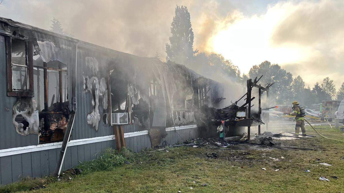 A Bellingham Fire Department firefighter works to extinguish a mobile home fire on June 25, 2023, at the Bakerview Estates mobile home community in Bellingham, Wash.