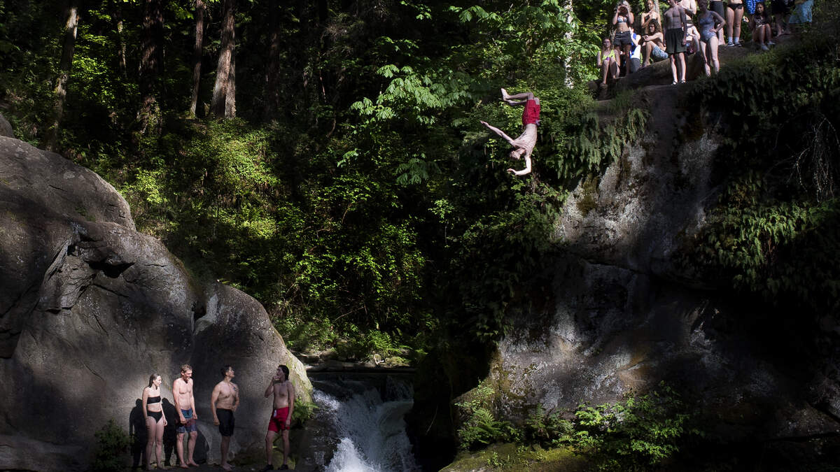 People take turns jumping from a cliff at Bellingham's Whatcom Falls Park in May. Signs warn of danger in jumping, but it's a popular place when the weather is hot.