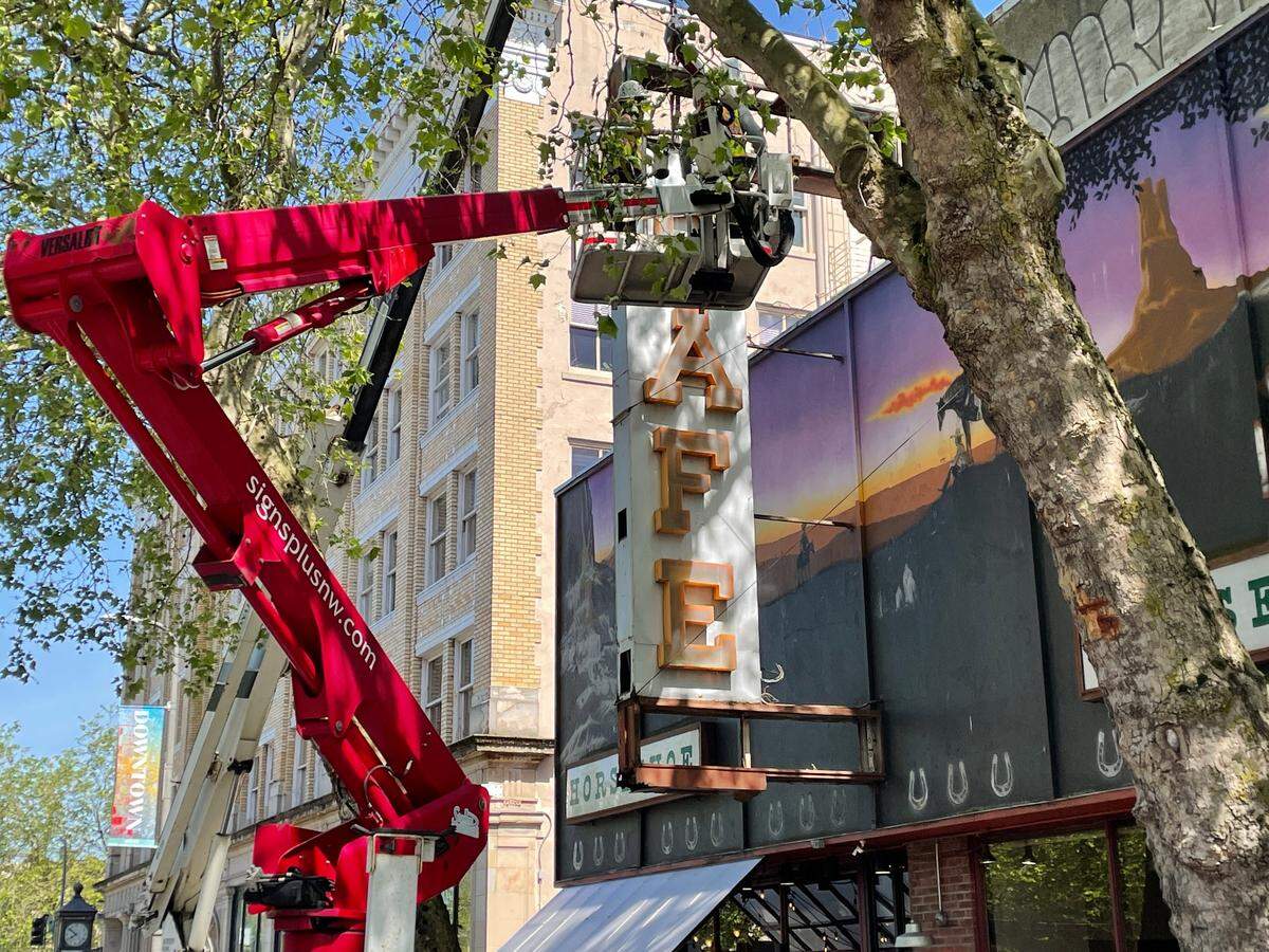Workers from Signs Plus begin removing the Horseshoe Cafe sign on Tuesday, June 7. The longtime Bellingham cafe is getting a new sign that will have a similar look but will be safer and have new features.