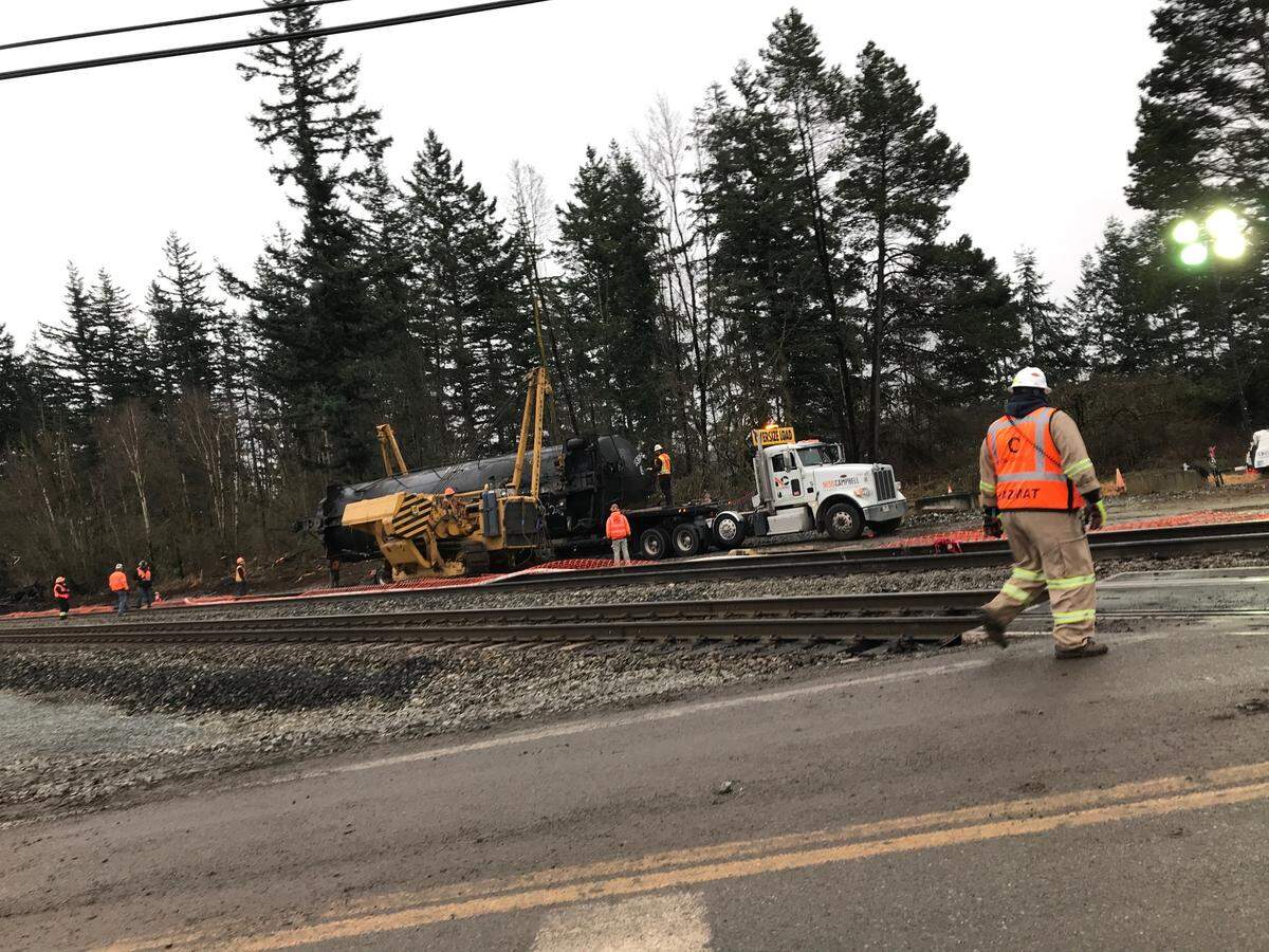 One of seven railroad tank cars damaged when an oil train derailed last week in Custer is moved Tuesday afternoon, Dec. 29. The damaged rail cars were lifted one by one onto a flatbed truck for transport to a BNSF Railway facility.
