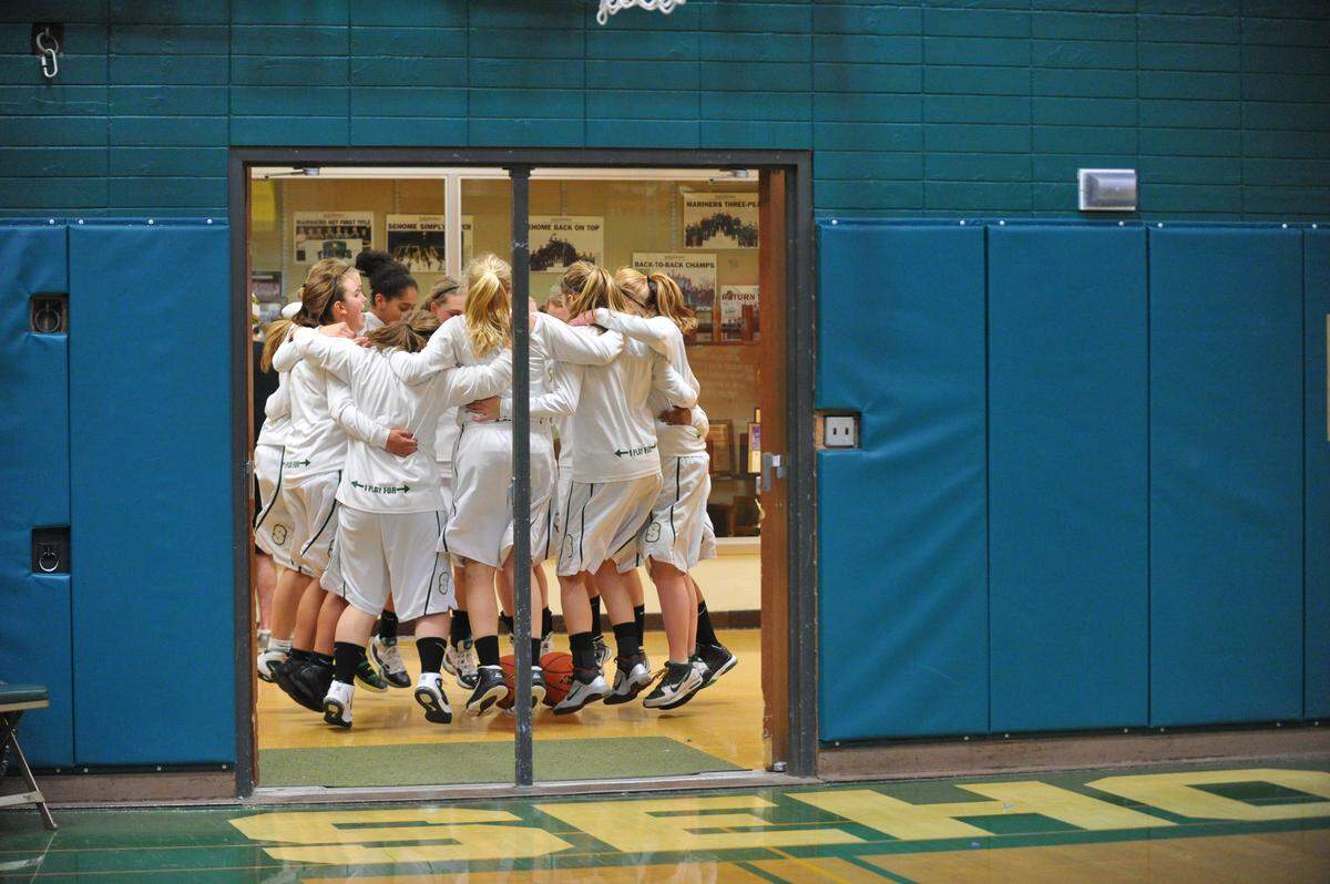 The Sehome girls’ basketball team cheers together in a hallway outside the gym before a 2011 game against Anacortes. Demolition of the old gym building at Sehome High School has uncovered more asbestos-wrapped pipes in the walls and flooring than anticipated, the school district says, but the health of students and staff has not been endangered.